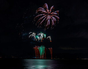 水上から上がる花火と緑に染まる海