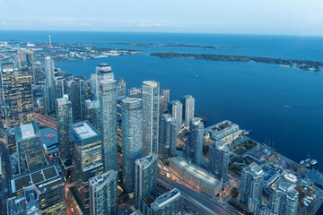 The view of downtown Toronto skyline skyscrapers from the top of CN tower. Lake at dawn, city light...