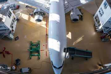 Top view of a white passenger airliner in the aviation hangar. Aircraft under maintenance. Checking...