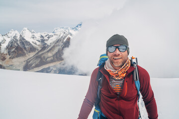 Cheerful laughing climber in sunglasses portrait with backpack ascending Mera peak high slopes at 6000m enjoying legendary Mount Everest, Nuptse, Lhotse with South Face wall beautiful High Himalayas.