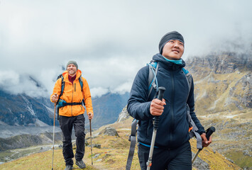 Caucasian and Sherpa men backpackers with trekking poles together hiking and enjoying Mera peak...