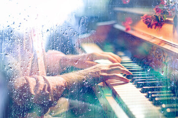 Concepto de música de piano fondo abstracto.
Tocando canción de piano detrás de la ventana con gotas de agua en un día lluvioso. Música triste para el viaje.