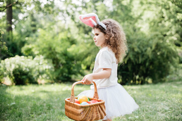 Easter egg hunt. Girl child Wearing Bunny Ears Running To Pick Up Egg In Garden. Easter tradition....