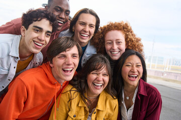 Group portrait of several cheerful young people smiling outdoors. Multiracial joyful friends posing together happy for photo. Community of generation z student having a good time enjoying free time.  - obrazy, fototapety, plakaty