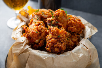 Bowl of deep fried chicken wings with bbq souse and beer on gray table close up