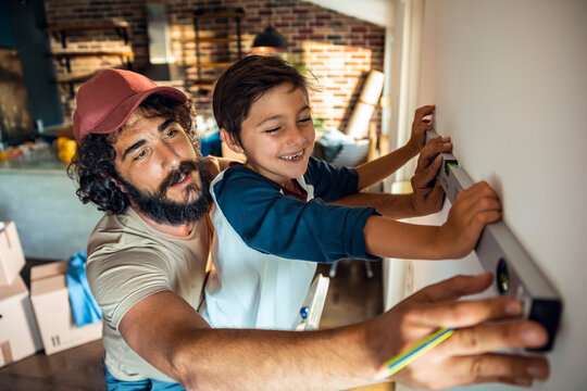 Father and son working together measuring wall for renovation