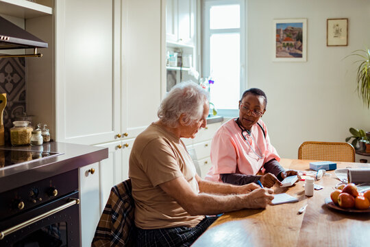 Senior man planning with caregiver about medication at home