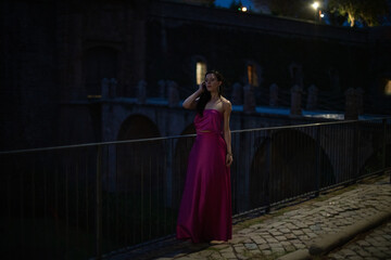 Woman in elegant dress on a castle at night