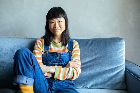 Asian Woman Sitting On Couch Looking At Camera