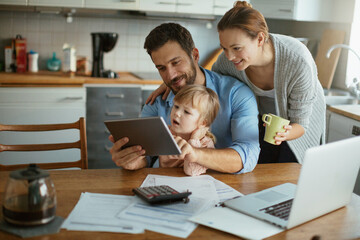 Young family using tablet with documents on desk - obrazy, fototapety, plakaty