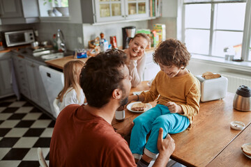 Happy family having fun in kitchen during breakfast