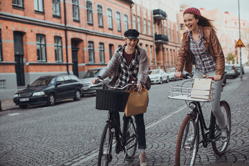 Two stylish young female friends biking in the city