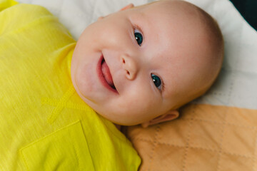 Portrait of a newborn baby in a yellow bodysuit.