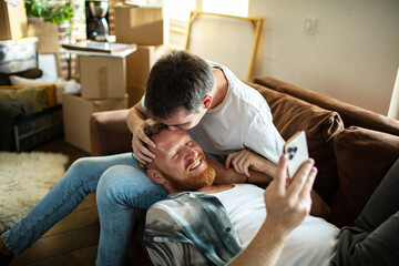 Young man kissing gay partner on forehead at home