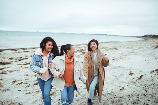 Three young women walking on cold beach together