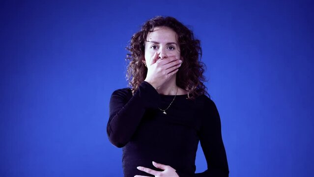 Woman Reacting to Shocking News by Hand Over Mouth on Blue background, Unbelief in Her Eyes