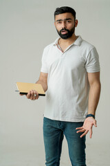 Young indian man standing with note book, isolated on white