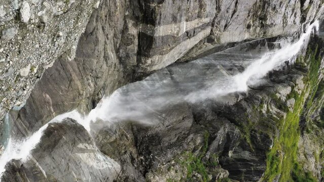 Long white jet of waterfall in rocky mountains. Beautiful high glacier waterfall falls from rocks. Karachay-Cherkess Republic. North Caucasus