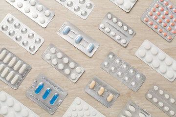 Pills in blister packaging on wooden background, top view