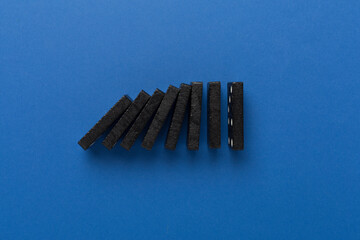 Black domino tiles on color background, top view