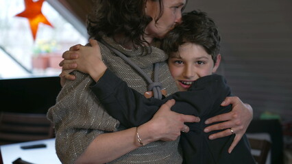 Mother and pre-teen small boy son embrace in authentic real life loving affectionate scene, family...