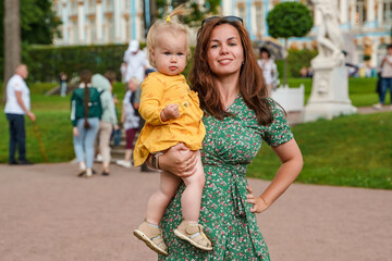 A young mother and child walk in the park with the Catherine Palace in Tsarskoye Selo in St....