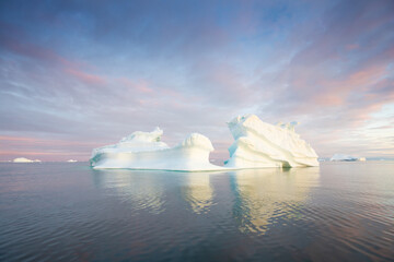 Arctic nature landscape with icebergs in Greenland icefjord with midnight sun. Early morning summer...
