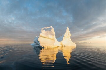 Obraz na płótnie Canvas Arctic nature landscape with icebergs in Greenland icefjord with midnight sun. Early morning summer alpenglow during midnight season. Hidden Danger and Global Warming Concept. Tip of the iceberg.
