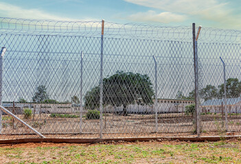 generic view of a prison fence with razor wire and barber wire rolls in top exterior yard