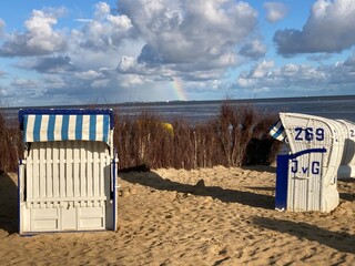 Strand von Cuxhaven an der Nordsee mit Blick zur Insel Neuwerk mit Regenbogen und Strandkörben