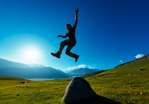 Athletic young man jumping on mountains background