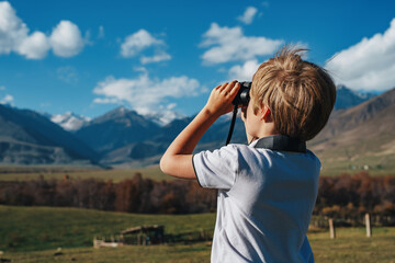 Boy with binoculars in the mountains looking into the distance