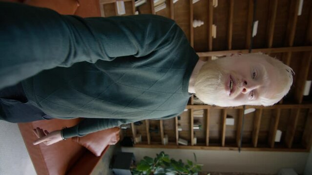 Vertical video of handsome albino man chatting online by video. Cheerful businessman having online conference with colleague in the loft office. Smiling guy talking with friend by video call 