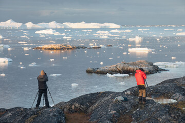Man taking picture with a digital SLR camera in west Greenland
Photographers in Ilulissat Icefjord, Greenland
Melting of a iceberg and pouring water into the sea - obrazy, fototapety, plakaty