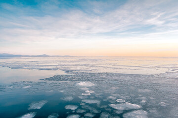 Sea winter landscape. Sea slush and ice floes on the sea surface in winter during sunset. Fabulous winter day by the sea.