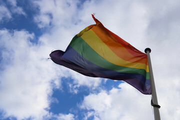 Rainbow flag on blue sky.