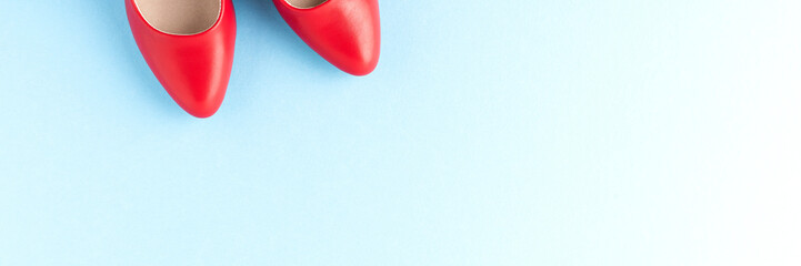 Red high heels on blue background with copyspace. Women’s shoes