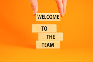 Welcome to the team symbol. Concept words Welcome to the team on wooden block. Beautiful orange table orange background. Businessman hand. Business, motivational and welcome to the team concept. - Powered by Adobe