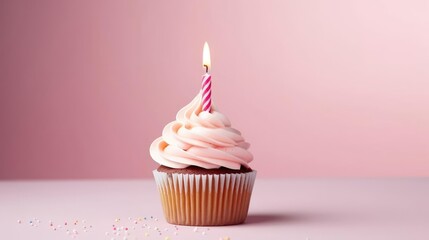 Birthday cupcake with a candle on a light pink background 