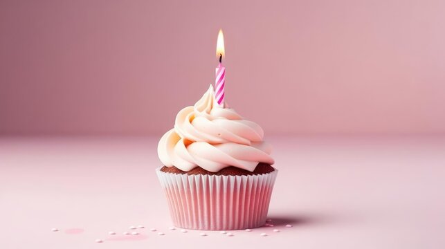 Birthday cupcake with a candle on a light pink background 
