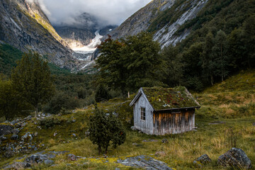 Old wooden cabin in the mountains. Glacier and forest. 