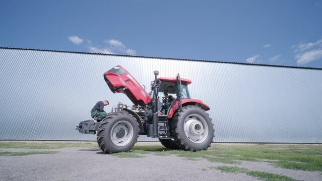 Farmer mechanic repairing tractor. Open tractor hood, engine. Repair agricultural technology