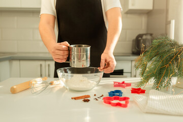 Male hands sifting flour for Christmas cookie recipe