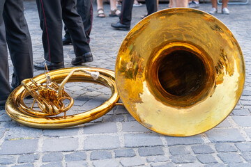 Brass tuba lying on the ground in a cobbled street with soldier musicians in the background