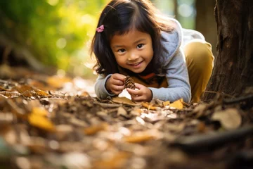 Deurstickers A young girl of Asian descent explores a forest, crouching to examine an animal track in the dirt. Her wide-eyed curiosity and connection with nature epitomize early outdoor learning. © Regina