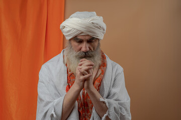 Senior man in a turban is associated with a Hindu, Jain, Buddhist.  Prayer gesture.