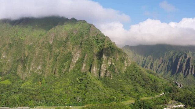 Scenic route on Oahu Hawaii island at golden sunrise. Interstate H3 passing through majestic green Koolau Mountains with Trans-Koolau twin tunnels. Aerial along highway with epic nature landscape view