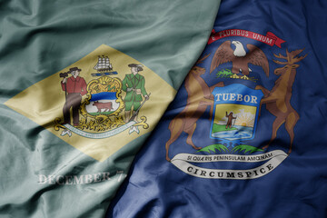 big waving colorful national flag of michigan state and flag of delaware state .
