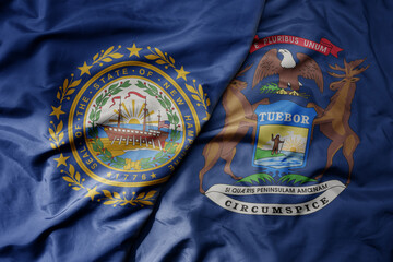 big waving colorful national flag of michigan state and flag of new hampshire state .