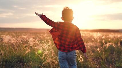 Boy overflowed with joy runs along field of plants at sunset with soaring spirit